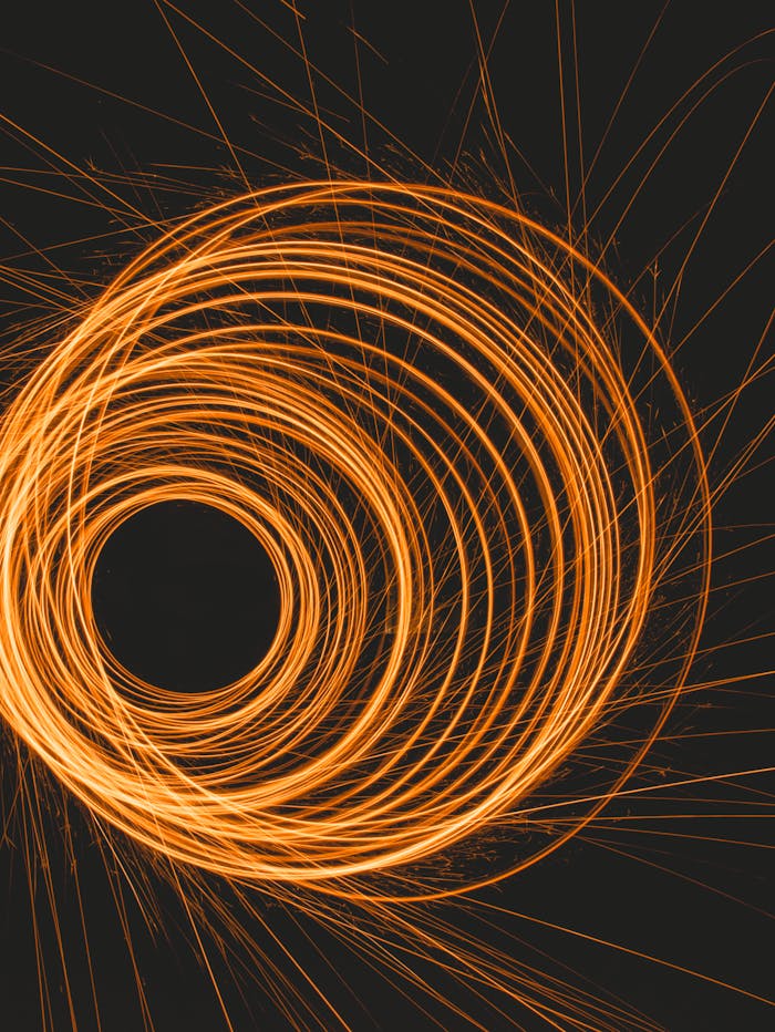 Explore the captivating motion of orange light trails captured in a mesmerizing spiral pattern.